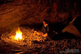 fire in cave with one person sitting crosslegged